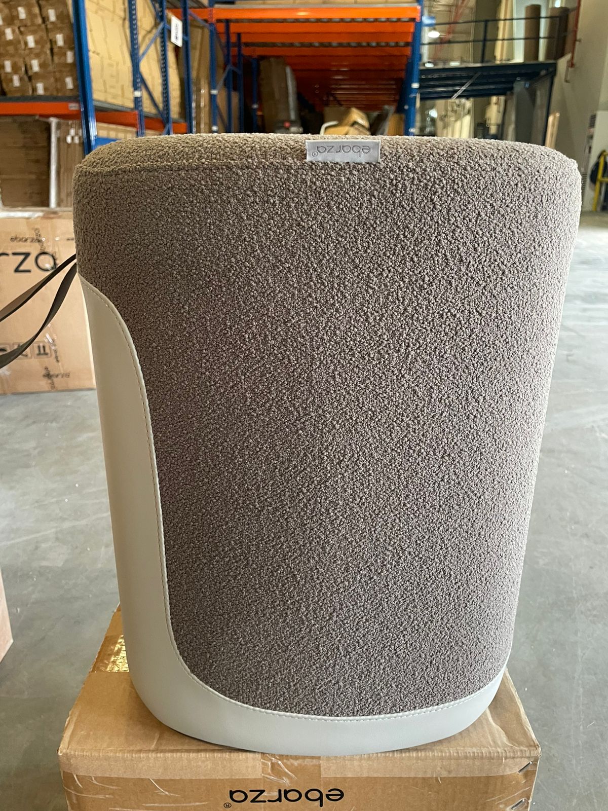 Grey Nomad fabric and PU pouf display item from BEACON, showcasing a versatile, cushioned ottoman with a modern design.