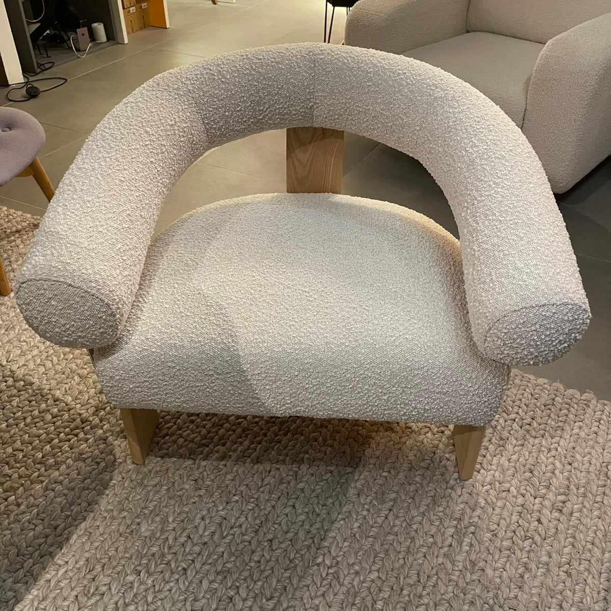 Display of Sagebrook Home curved back wishbone chair with brown oak legs, showcasing its elegant design and light-colored upholstery.