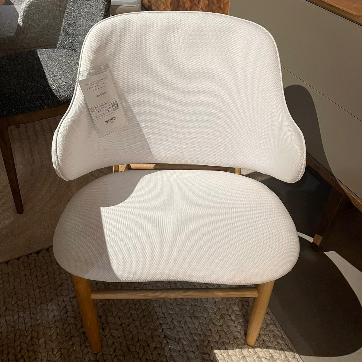Display lounge chair with solid ash wood base, showcasing modern design and plush upholstery, by Beacon.