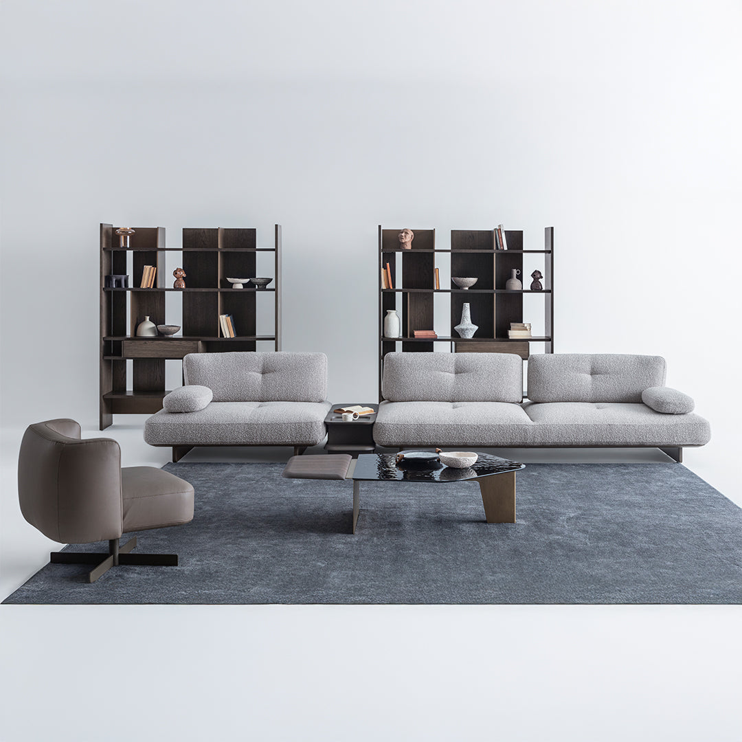 Modern living room with a gray sectional sofa, armchair, and bookshelves.