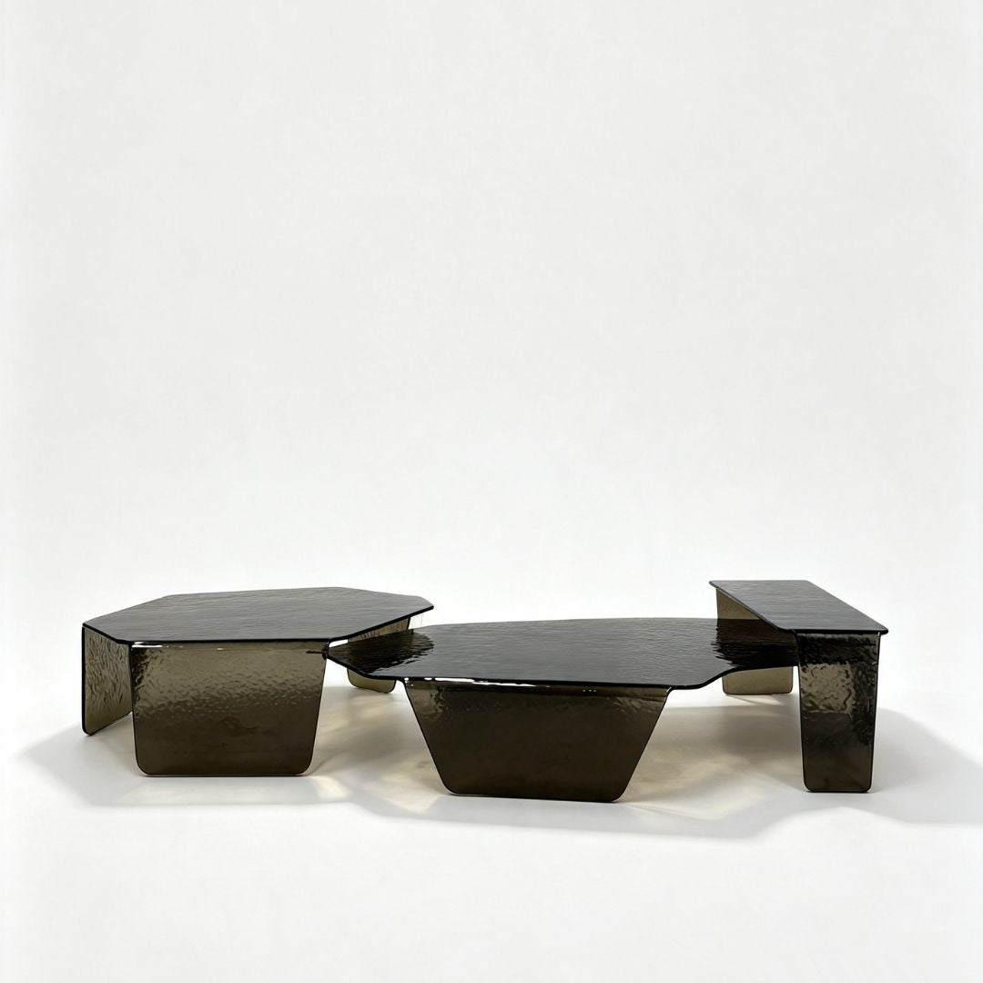 Three modern low coffee tables with a glossy, hammered dark metallic finish, arranged together on a seamless white studio background.