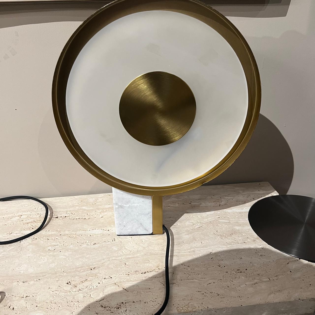 A beige Aalborg marble table lamp by Beacon on a sleek display stand, showcasing its elegant design and smooth marble surface.