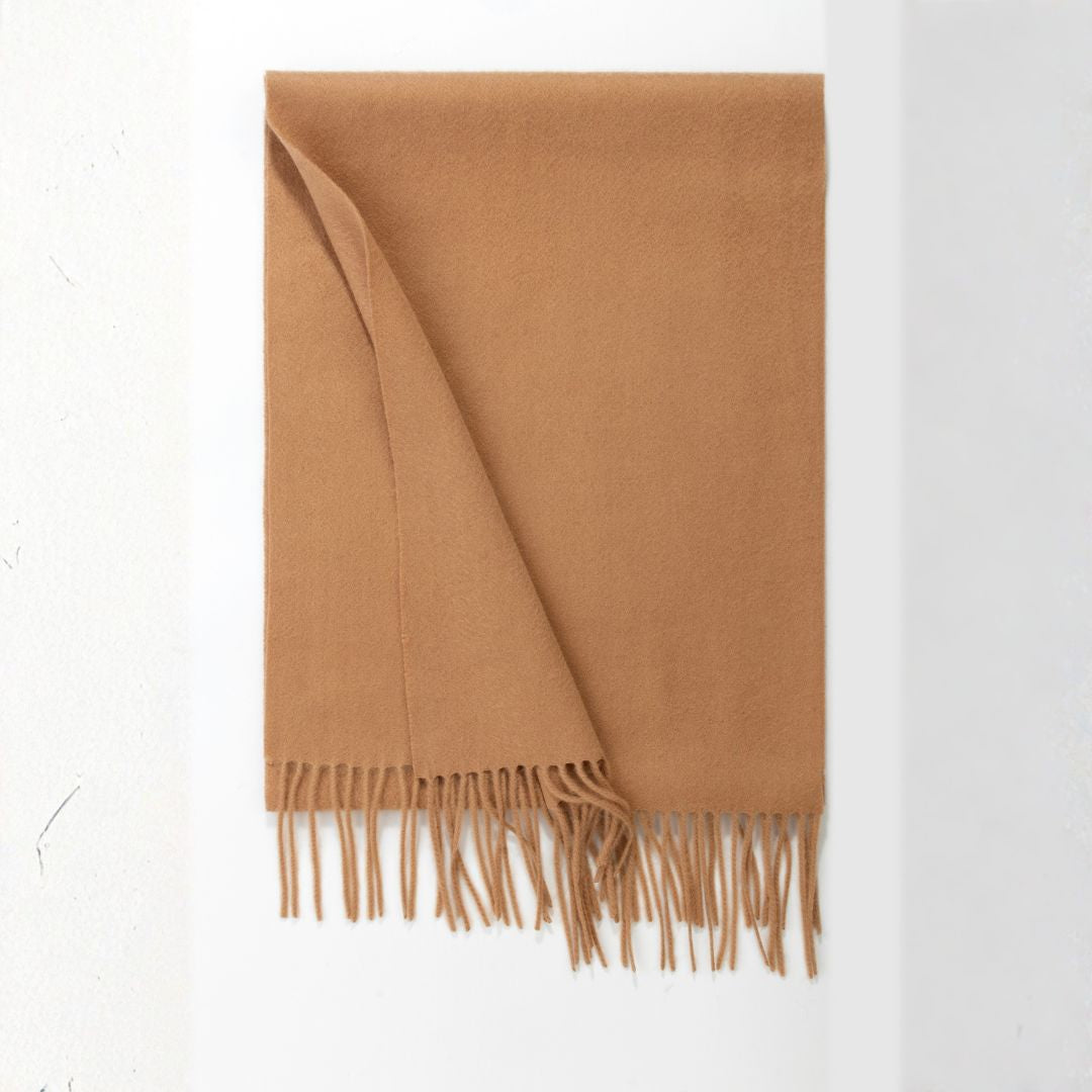 Beige Lana wool scarf from BEACON draped over a chair, showcasing its soft texture and cozy design.