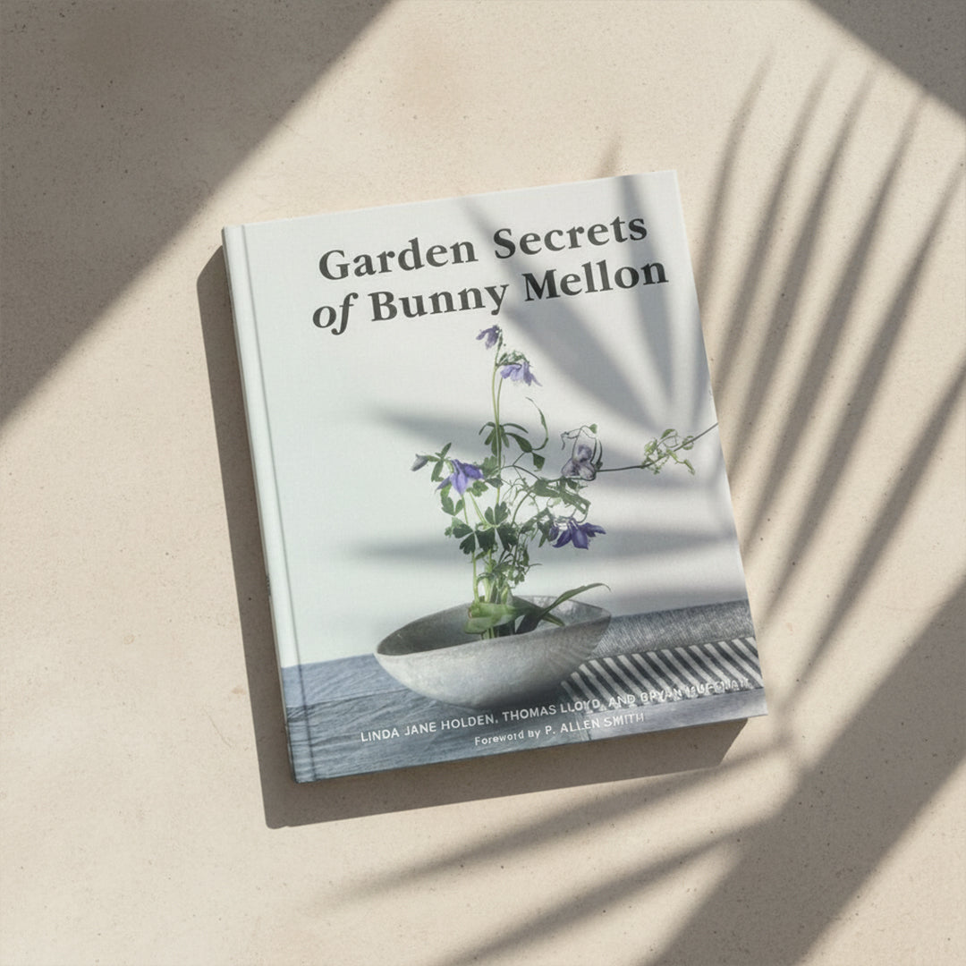 Decorative book titled "Garden Secrets of Bunny Mellon" by BEACON, featuring garden design and floral illustrations.