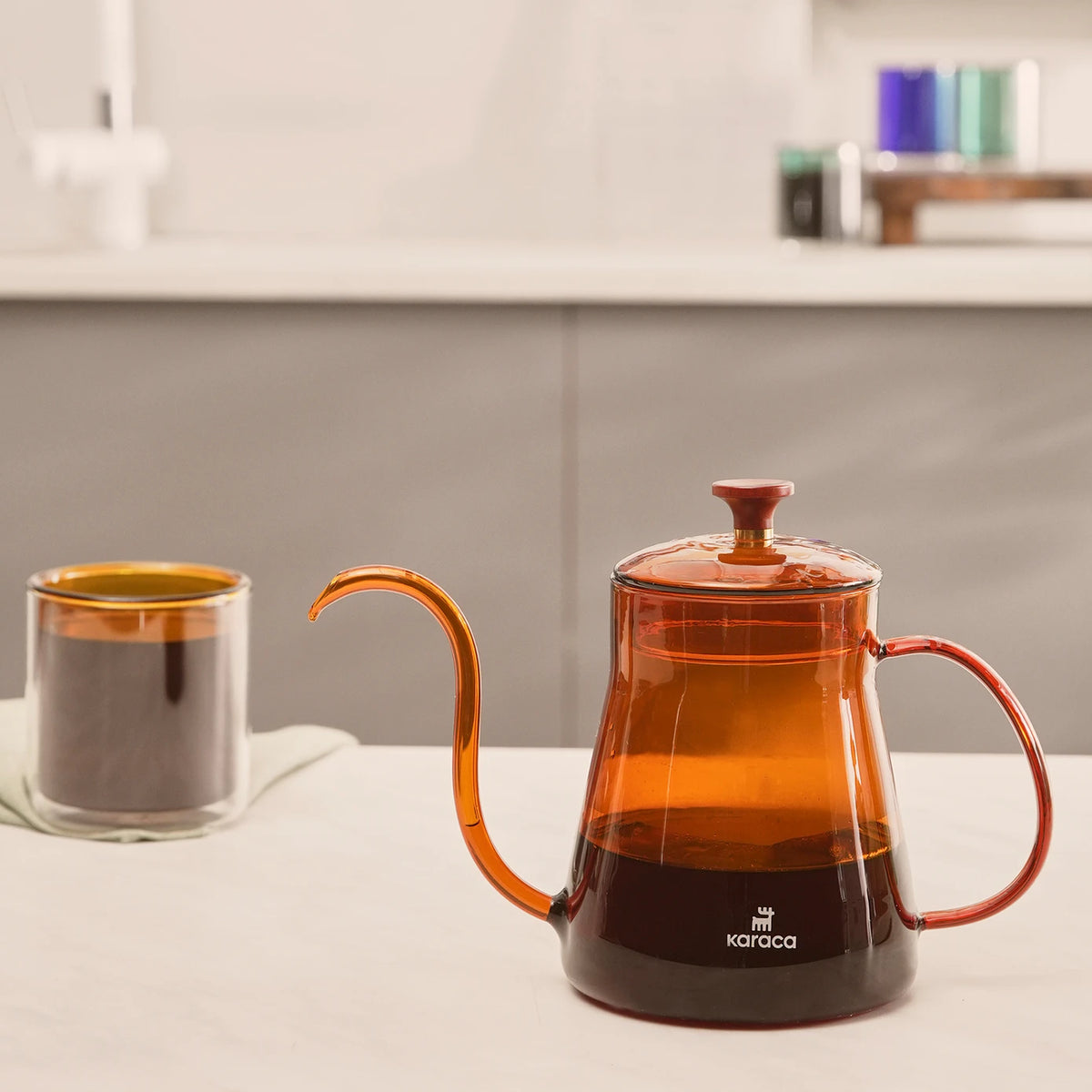 Karaca Martina orange borosilicate glass coffee kettle with 600 ml capacity, featuring a sleek handle and spout for brewing coffee or tea.