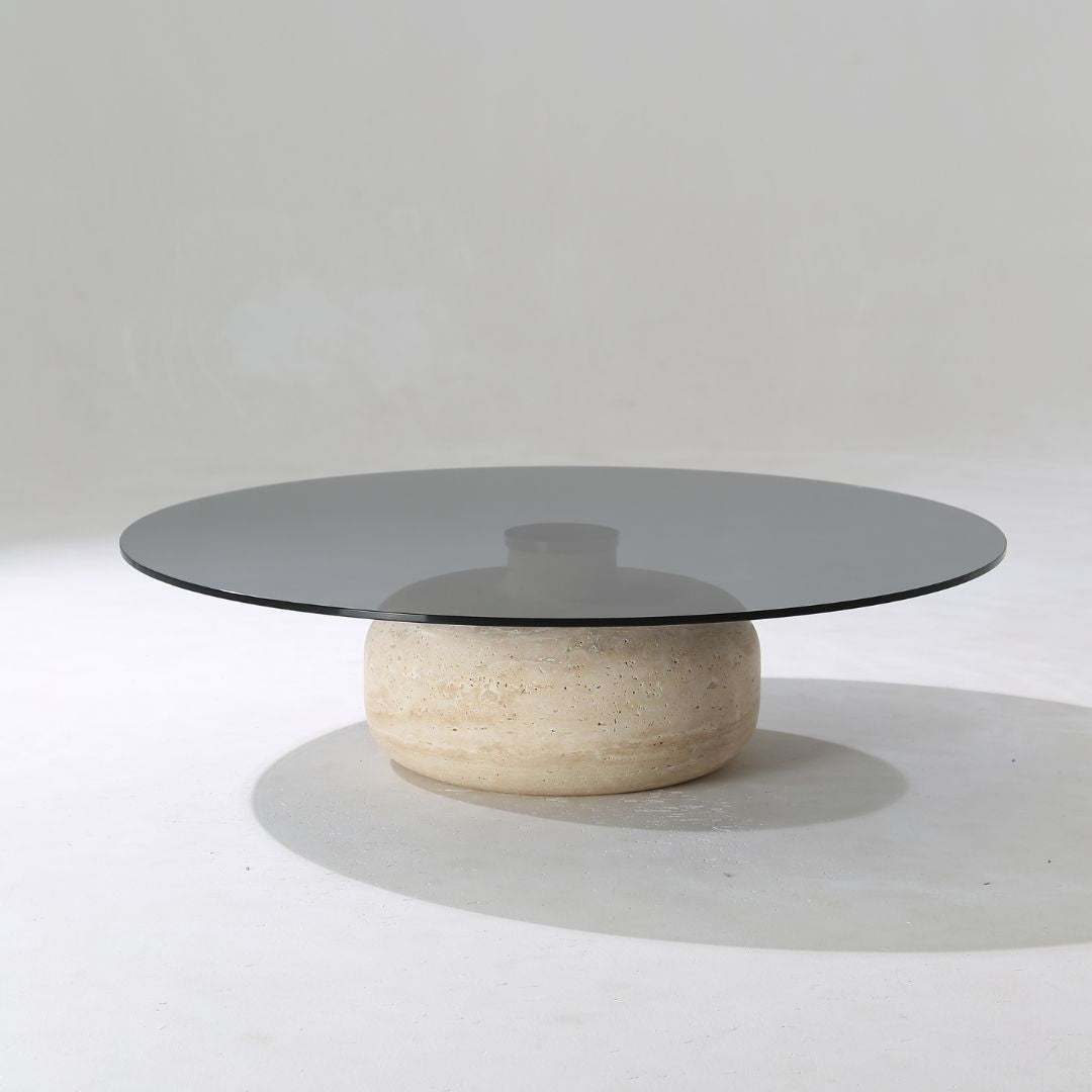 Minimal grey glass and travertine marble round coffee table by BEACON, featuring sleek modern design and elegant materials.