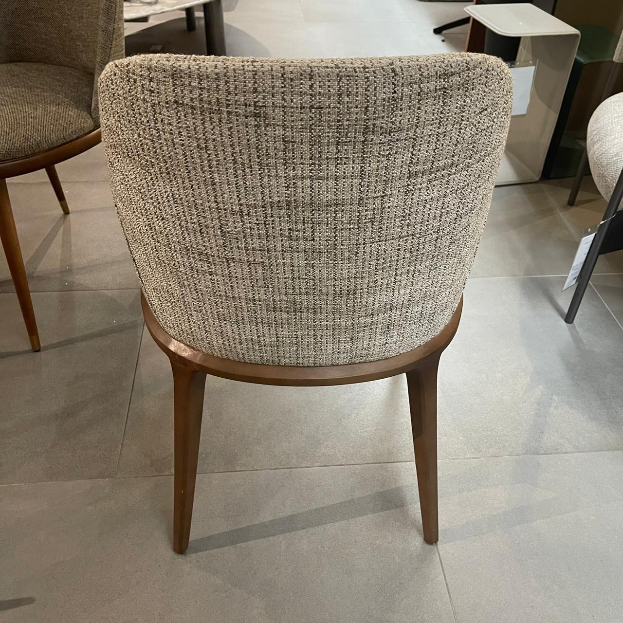 Genova dining chair with arms by YOL LIVING, showcasing a modern design and wooden frame, displayed as a store model.