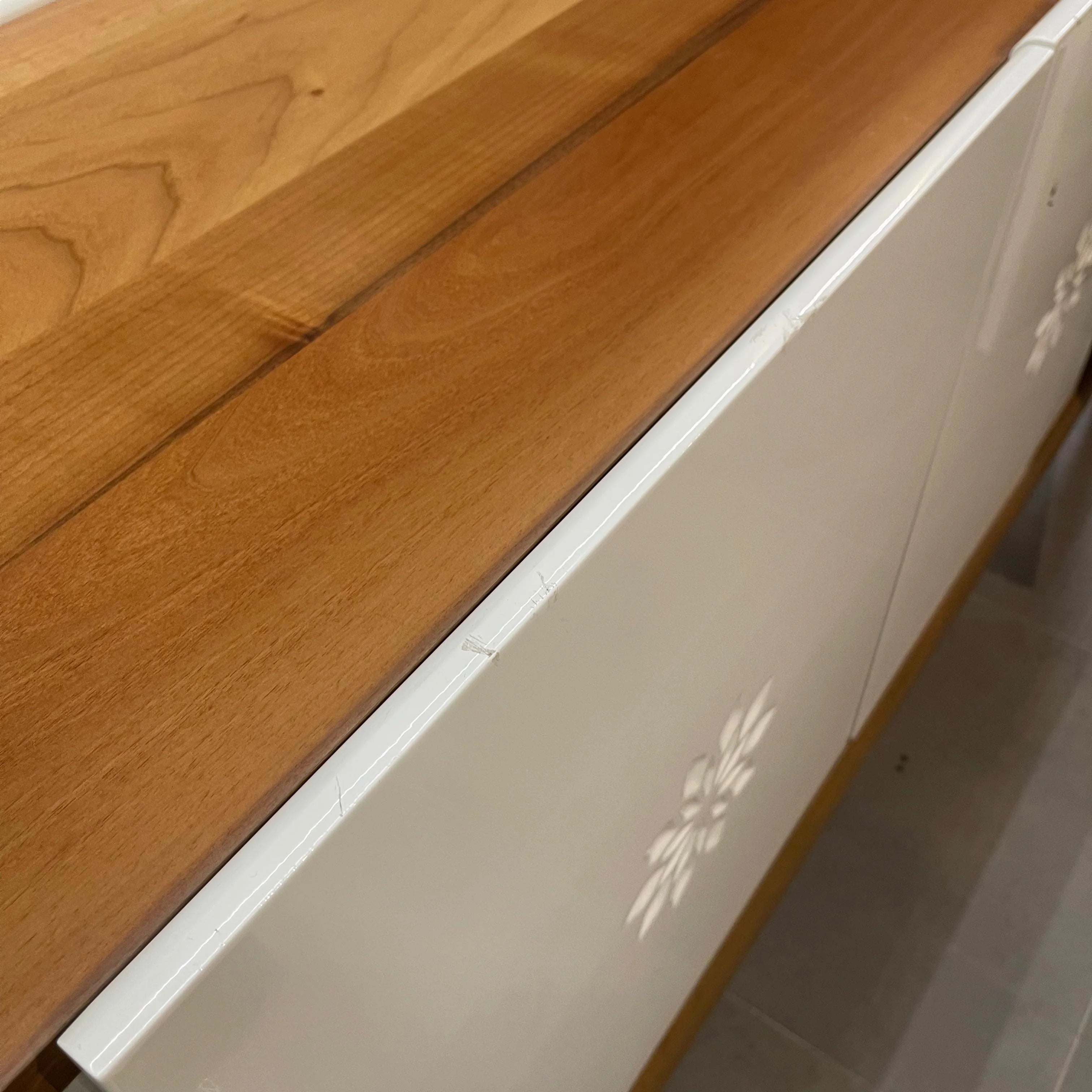 Close-up of a wooden surface and white cabinet with a floral design.