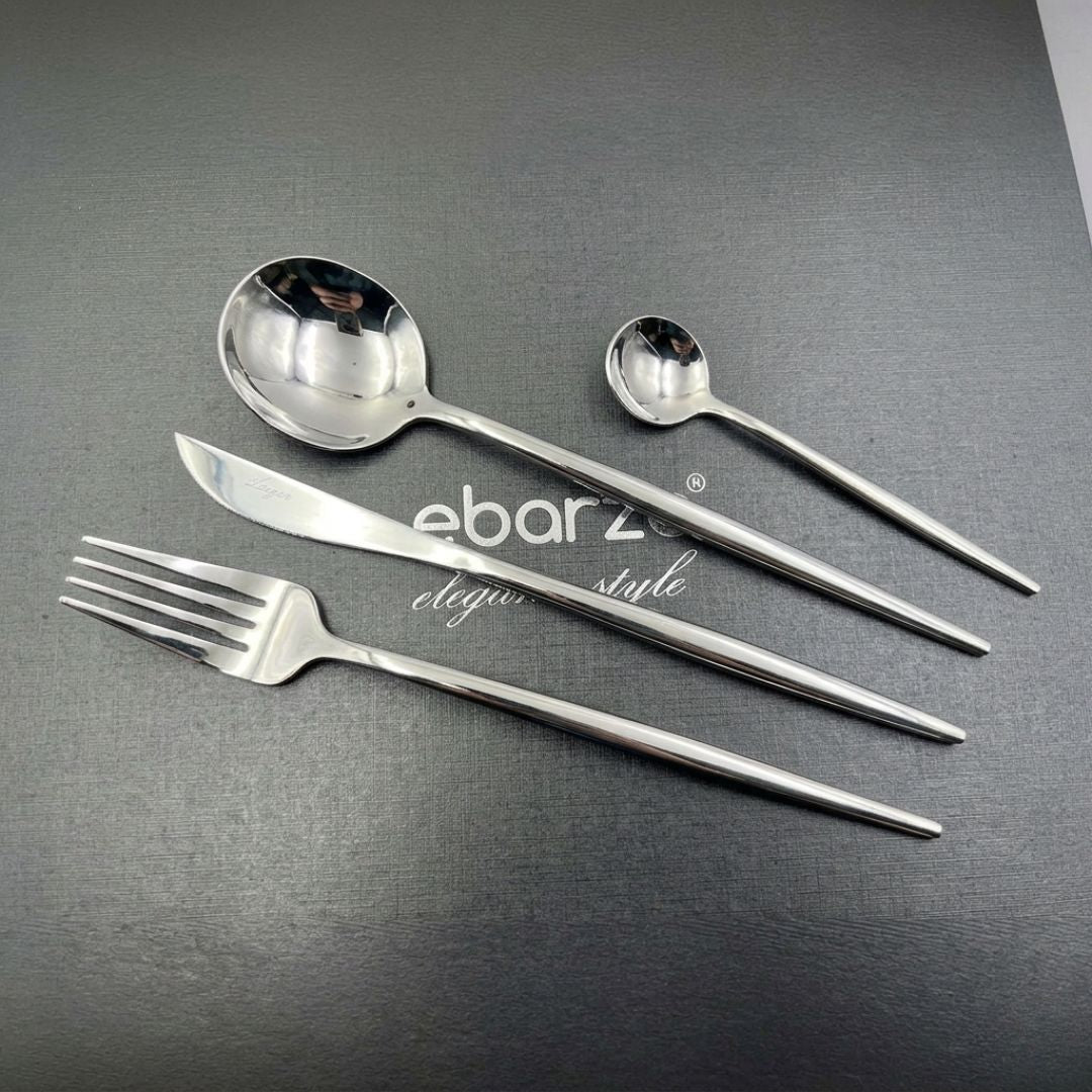 Obsidian 24-piece shiny silver cutlery set by BEACON, includes forks, knives, spoons, and serving utensils on a white background.