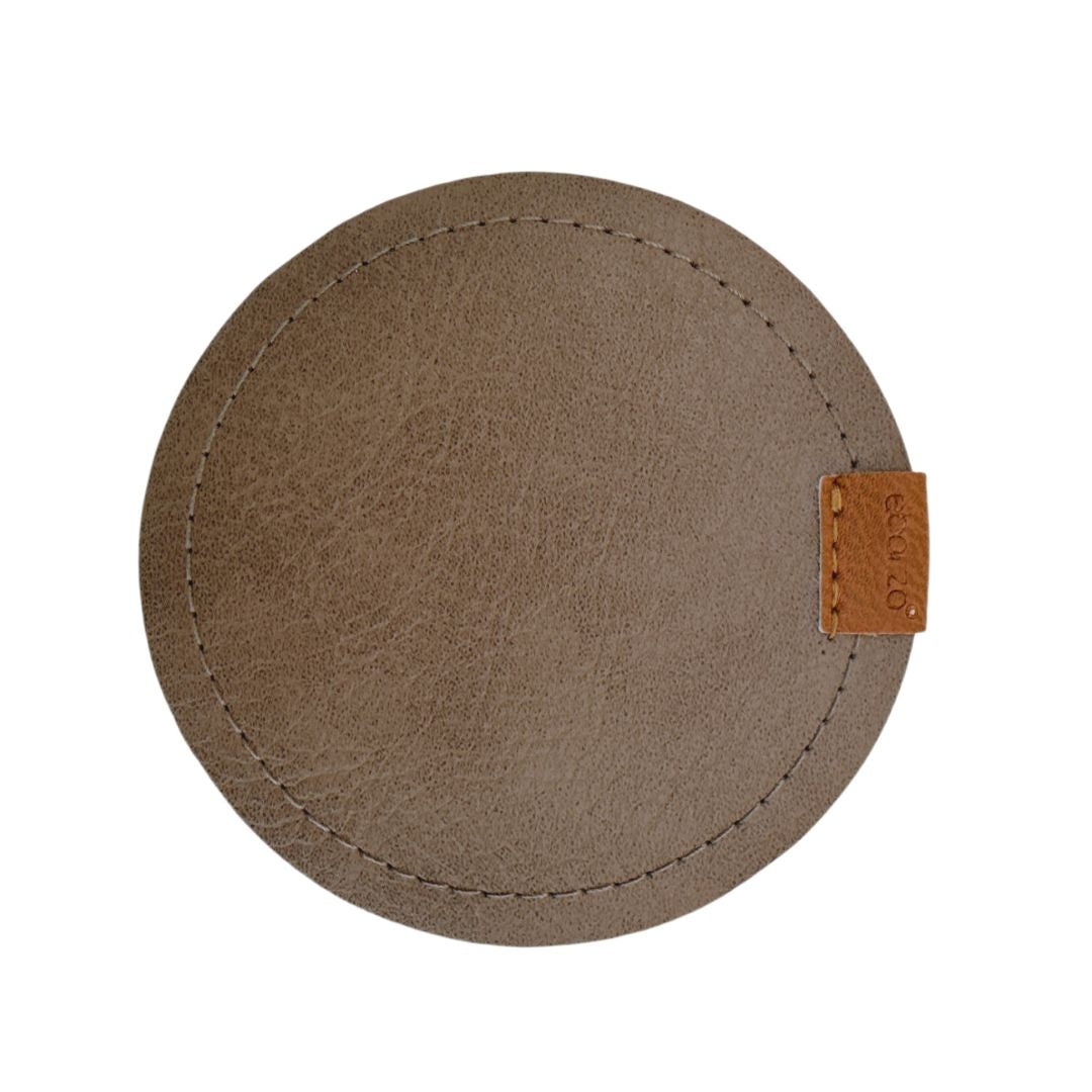 Set of four taupe grey coasters from BEACON, round drink coasters with a smooth finish, arranged on a wooden table.