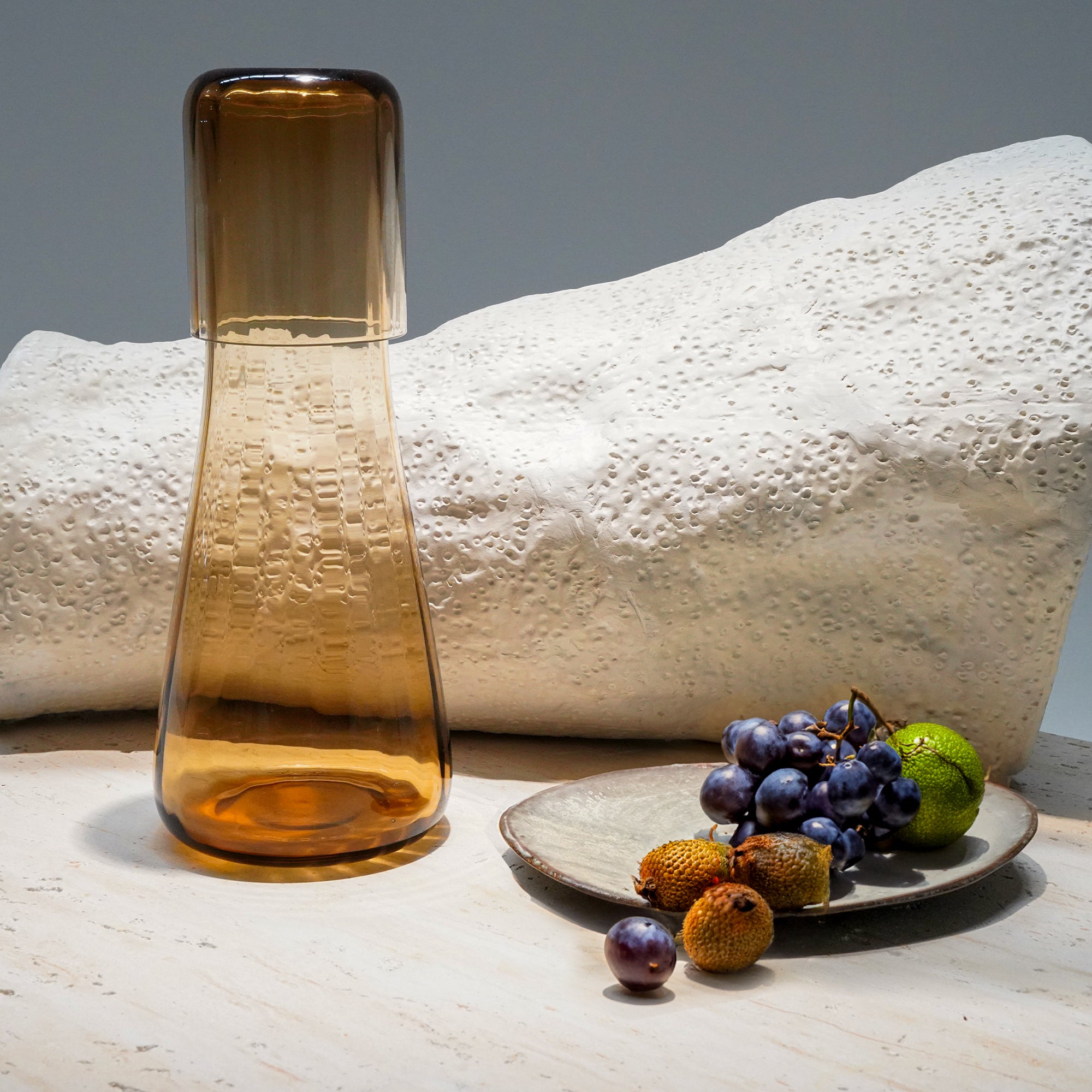 Amber glass carafe with matching tumbler, 1.2L and 150ml drinkware set from BEACON, featuring sleek amber-colored design.