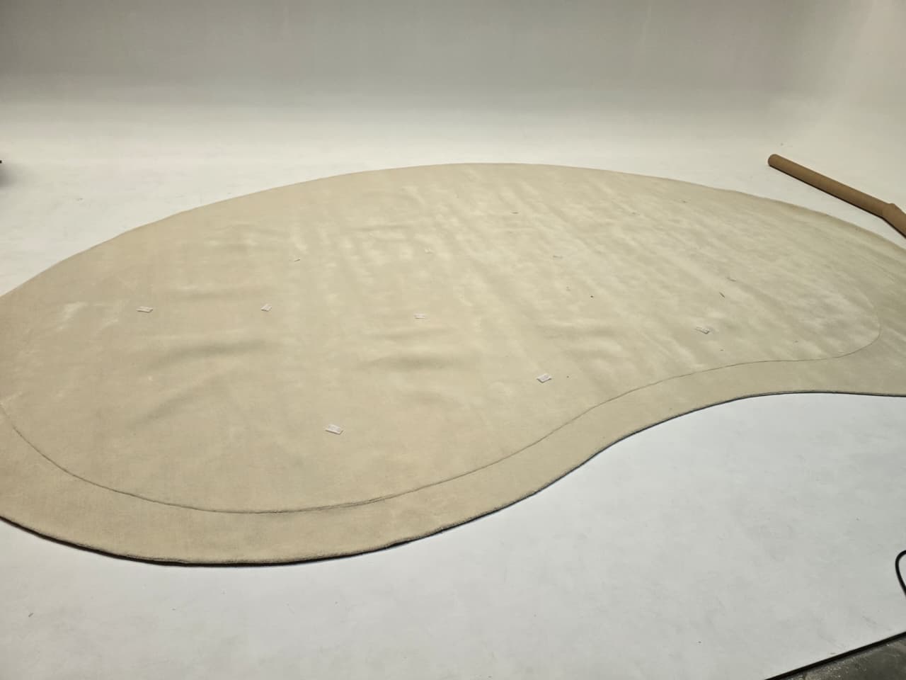 Display of a beige wool rug measuring 600x400 cm, by Javi, showcasing its soft texture and large size.