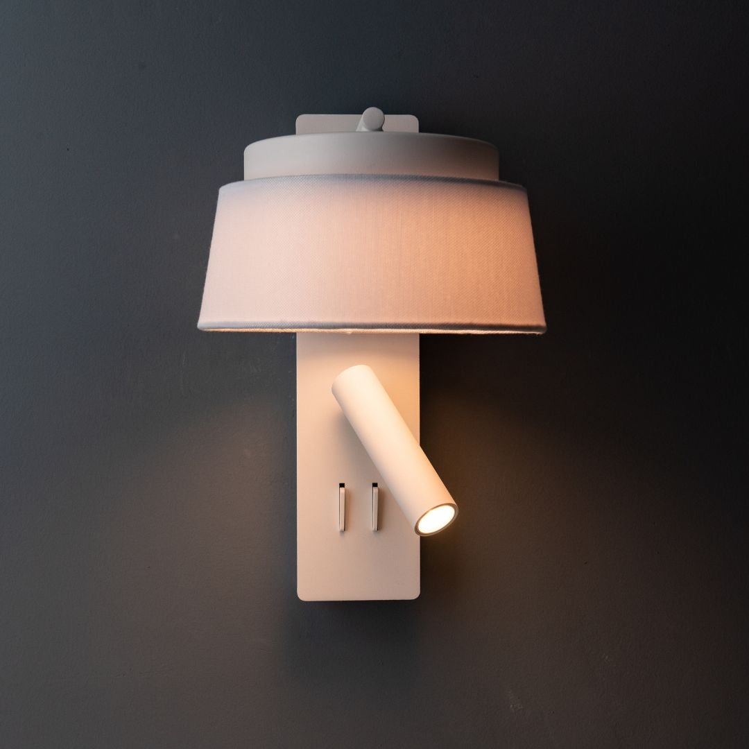 BEACON Calm WLB hotel-style wall reading lamp with white and grey linen shade, mounted on a wall for cozy lighting.