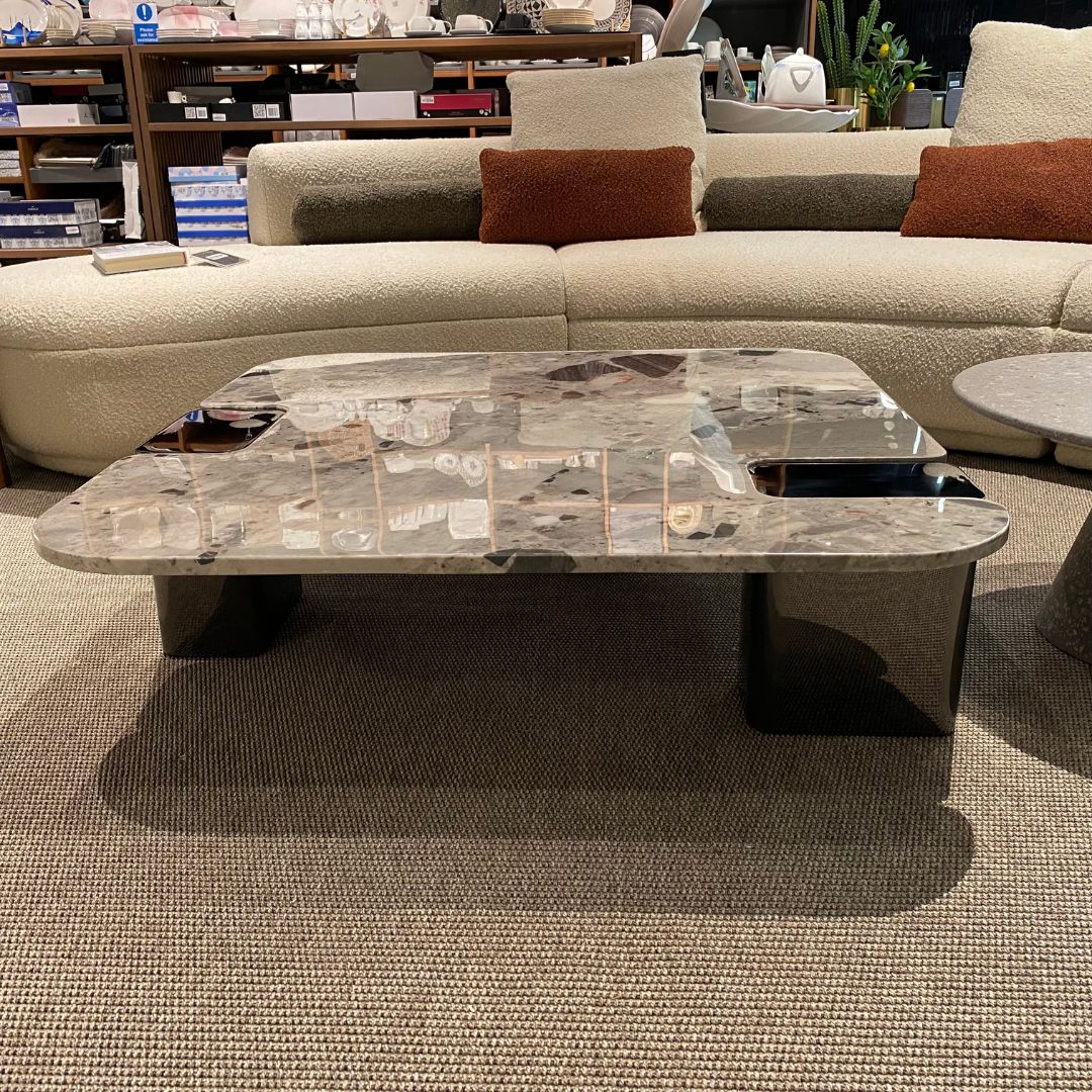 Modern coffee table with a natural stone top and sleek stainless steel legs, designed by BEACON.