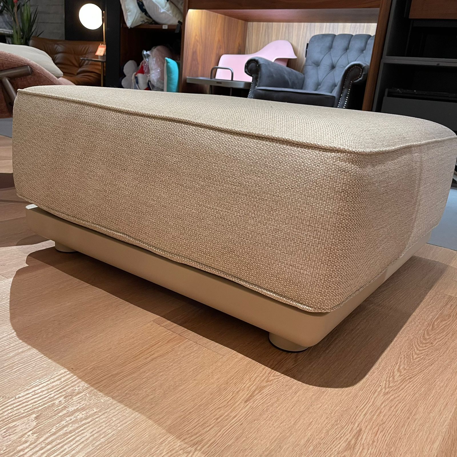 Display of a beige outdoor pouf with a square shape, made by Beacon, model KC8609N25ALU, used as a display item.