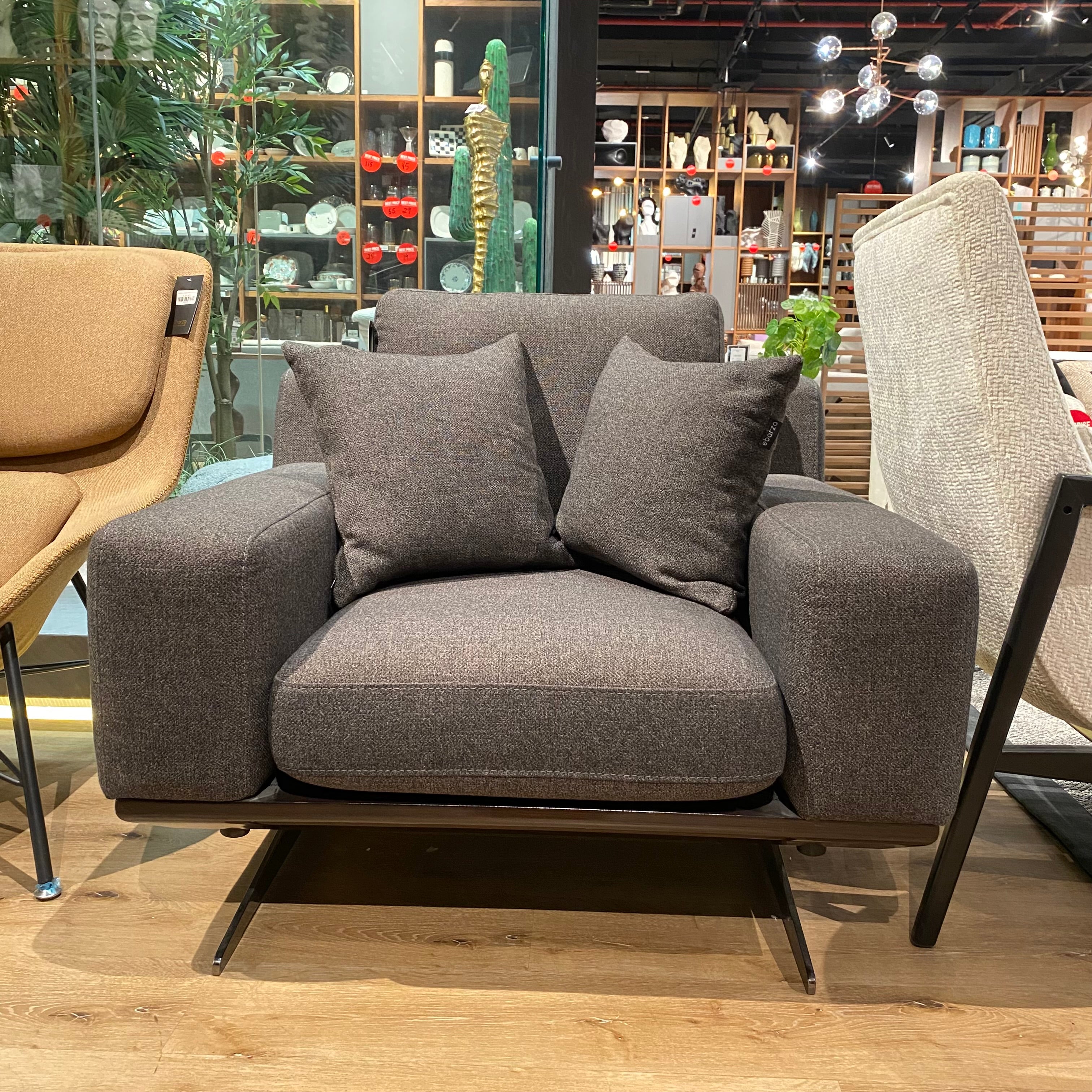 Elegant NILLS Furniture Design armchair with plush fabric upholstery and wooden legs, showcased as a display item.