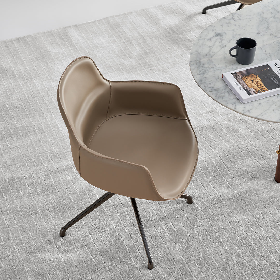 Beige saddle leather dining chair with contoured seat and wooden legs, designed for comfortable dining room seating.