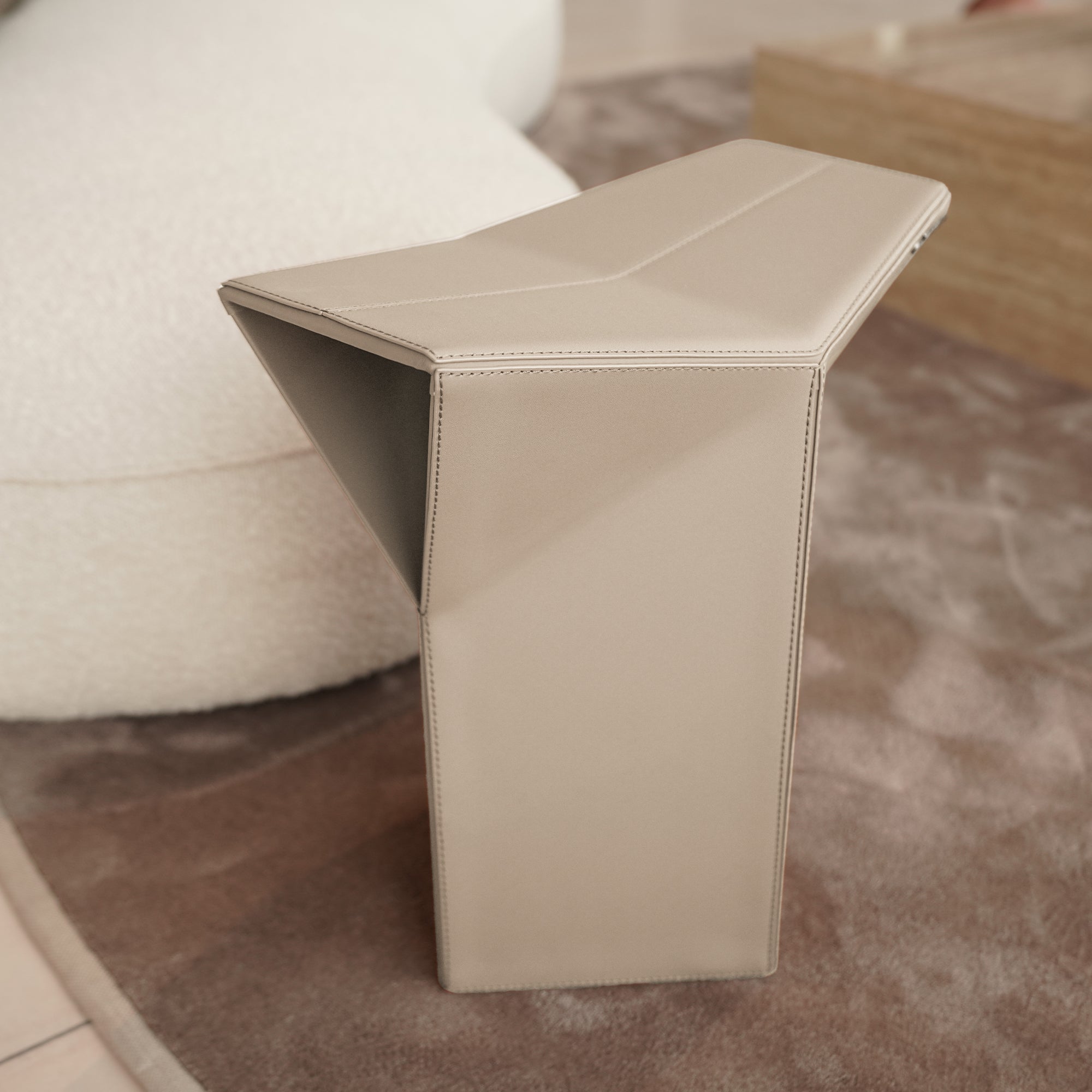 Beige microfiber saddle leather side table or low stool by BEACON, versatile pouf with a stylish, cushioned design.