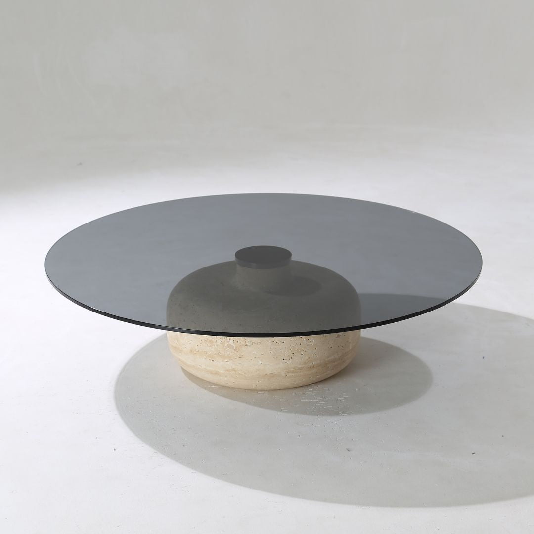 Minimal grey glass and travertine marble round coffee table by BEACON, showcasing sleek modern design and smooth surface.