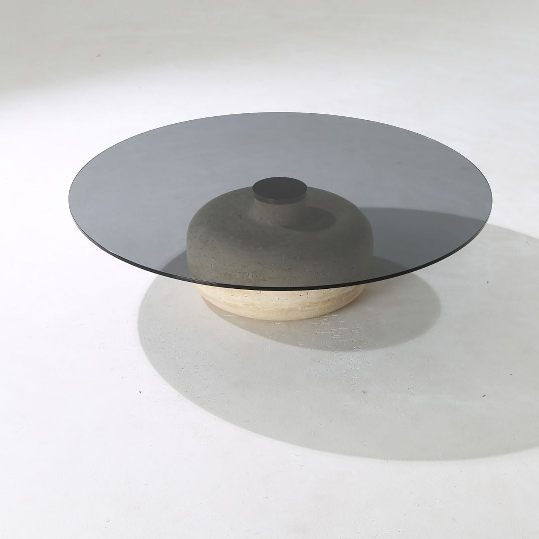Minimal grey glass and travertine marble round coffee table by BEACON, featuring a sleek modern design and smooth surface.