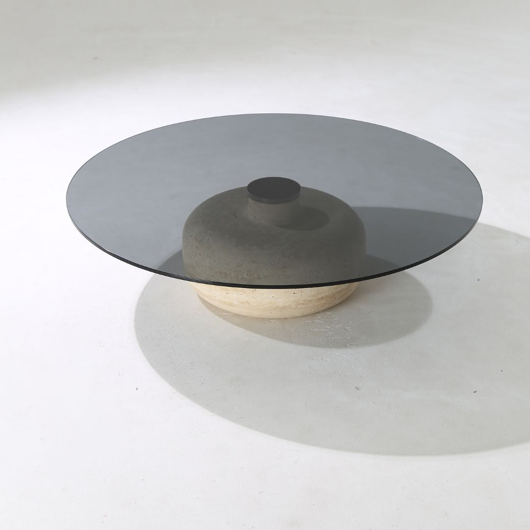 Minimal grey glass and travertine marble round coffee table by BEACON, showcasing sleek modern design and smooth surfaces.
