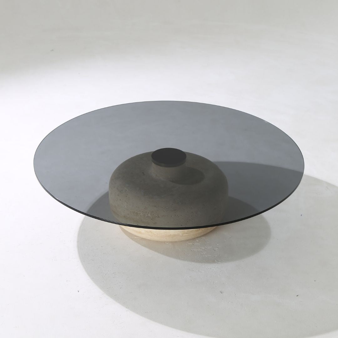 Minimal grey glass and travertine marble round coffee table by BEACON, showcasing sleek modern design and elegant materials.