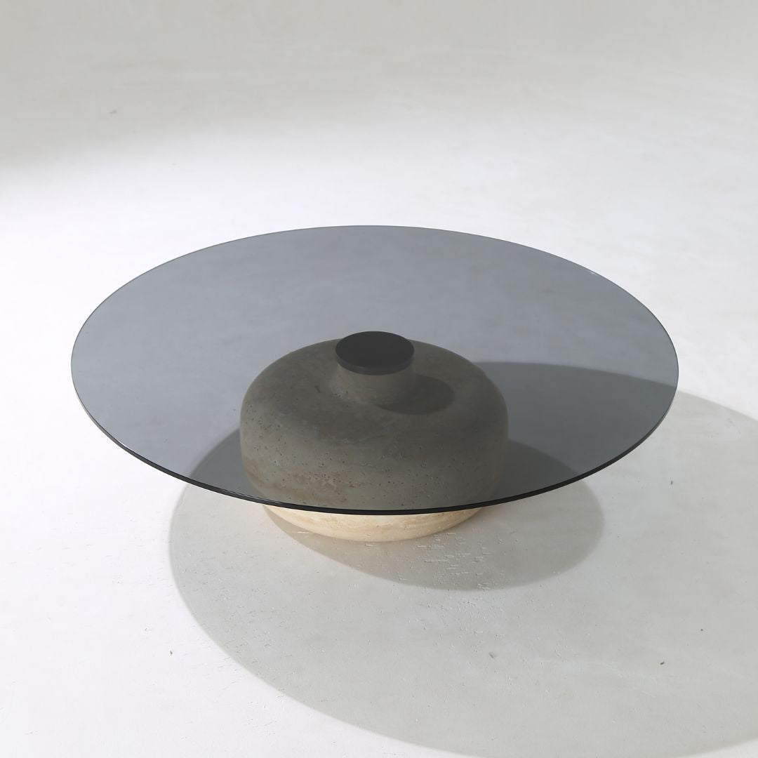 Minimal grey glass and travertine marble round coffee table by BEACON, showcasing a sleek modern design and smooth surface.