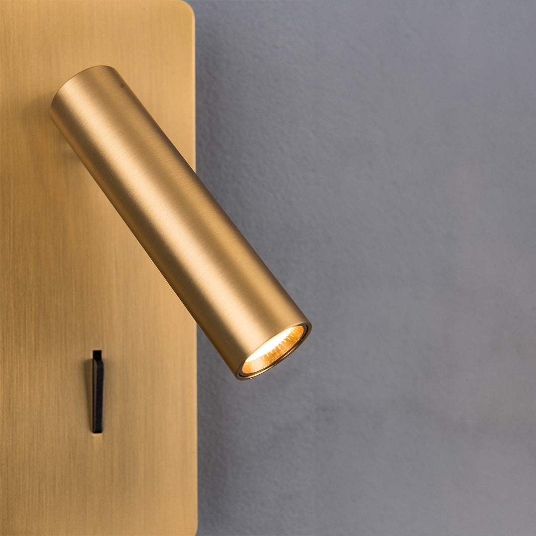 Gemini Hotel Style Wall Reading Lamp by BEACON, mounted on headboard, with sleek design and warm-brass finish, ideal for bedside reading.