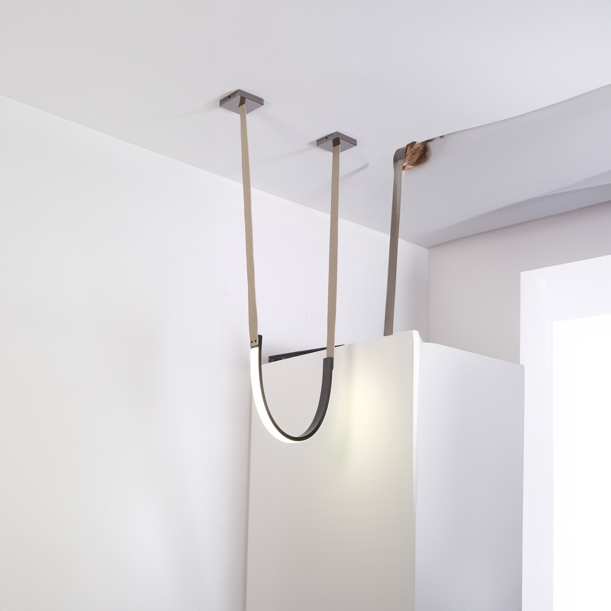 Set of three BEACON leather curve pendant lamps with sleek, modern design, hanging cords with leather accents.
