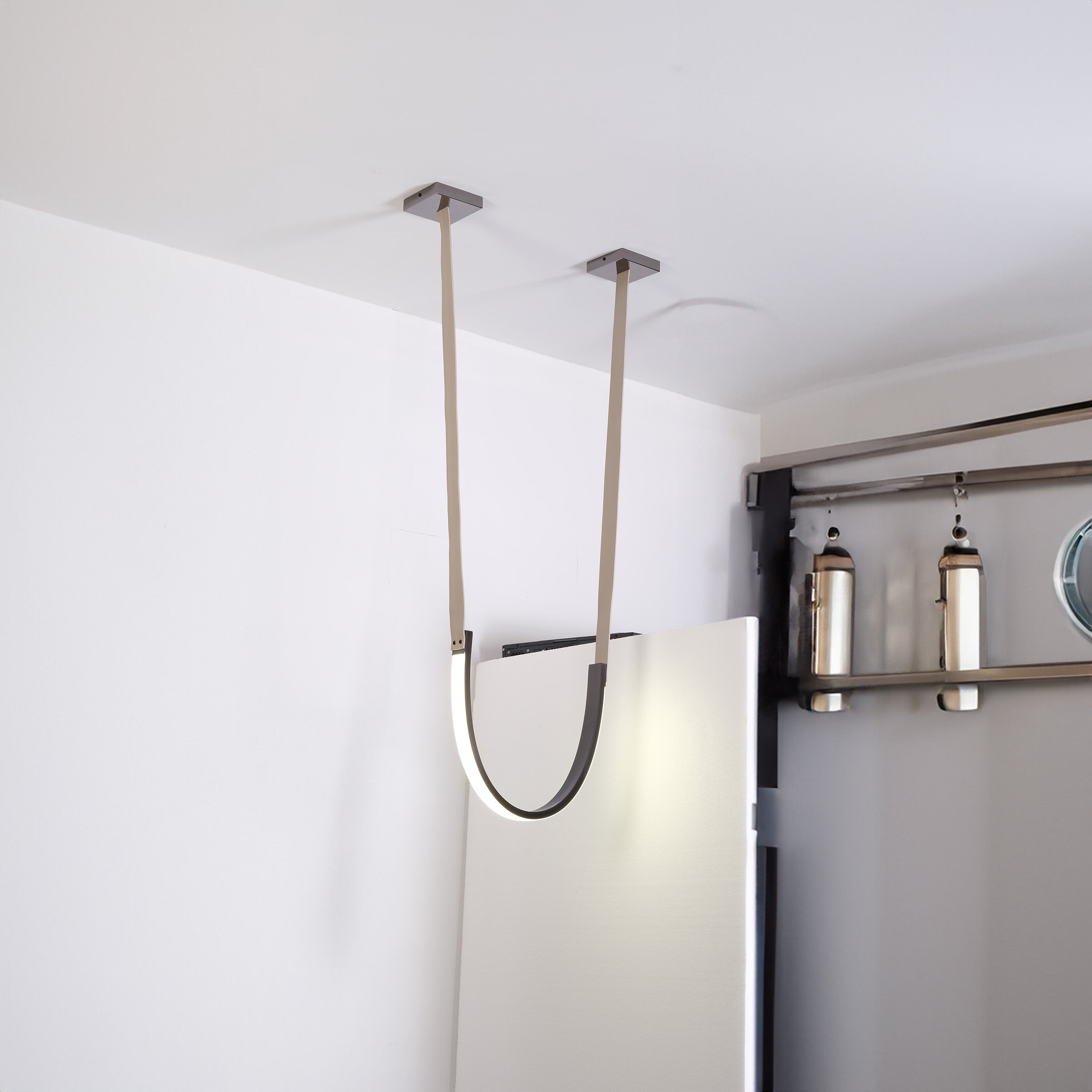Set of three BEACON Catenary Leather Curve Pendant Lamps hanging with curved leather cords and sleek modern design.